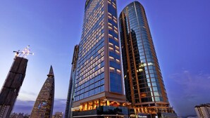 Un hotel moderno de gran altura, con fachada de vidrio, varios pisos y una entrada destacada.