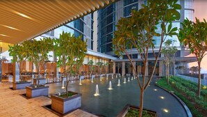 Un amplio patio interior con múltiples fuentes, plantas en macetas y un edificio moderno al fondo.