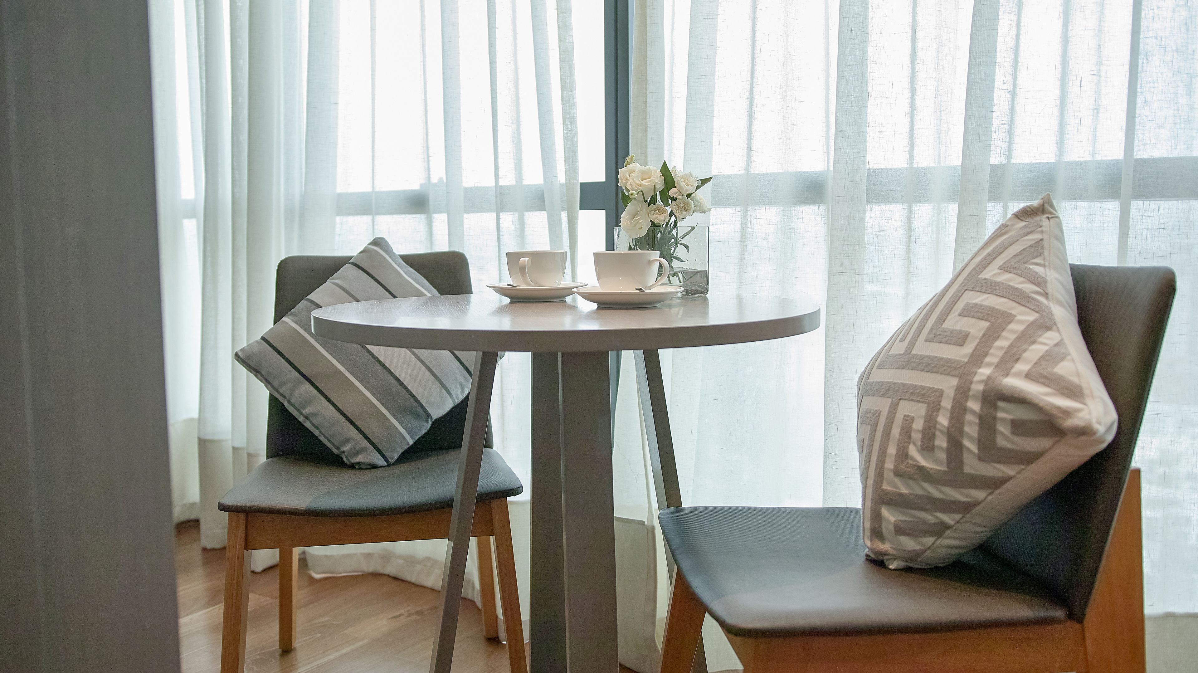 Un coin repas avec une table ronde, deux chaises et un vase rempli de fleurs.