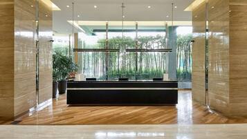 Un área de recepción moderna con suelo de madera, divisiones de vidrio y vistas al exterior.