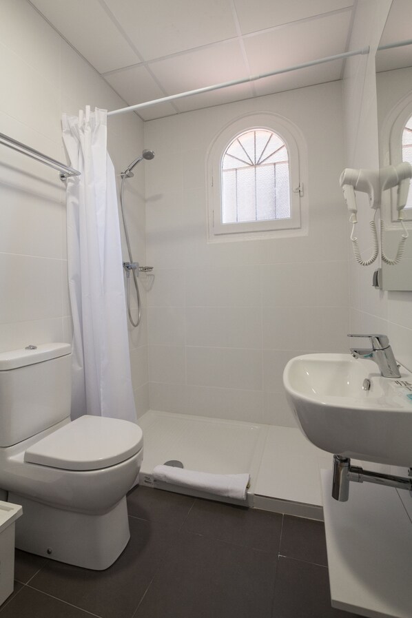 Un baño con inodoro, ducha y lavamanos.