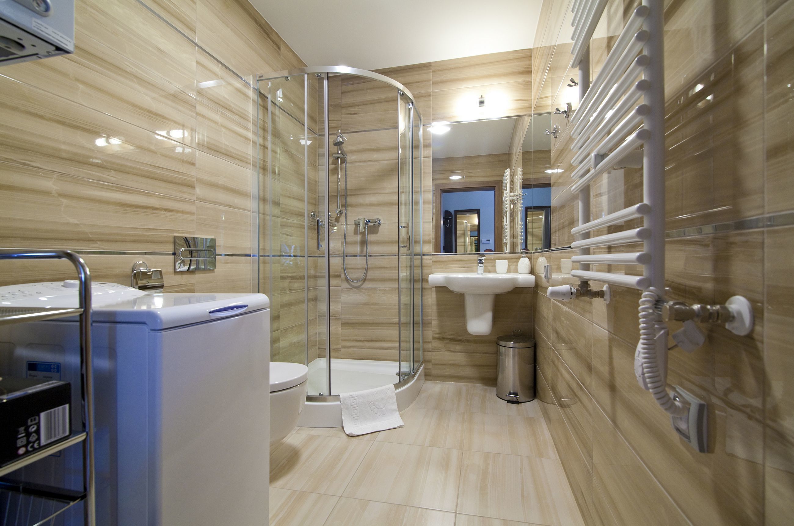 Un baño moderno con cabina de ducha de vidrio, un lavamanos blanco y un inodoro.