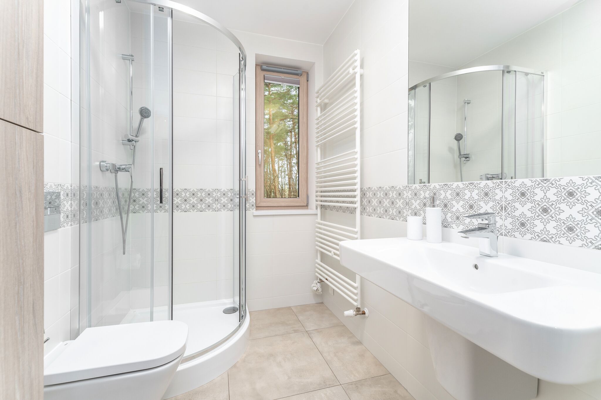 A modern bathroom with a glass-enclosed shower, a white sink, and a toilet.