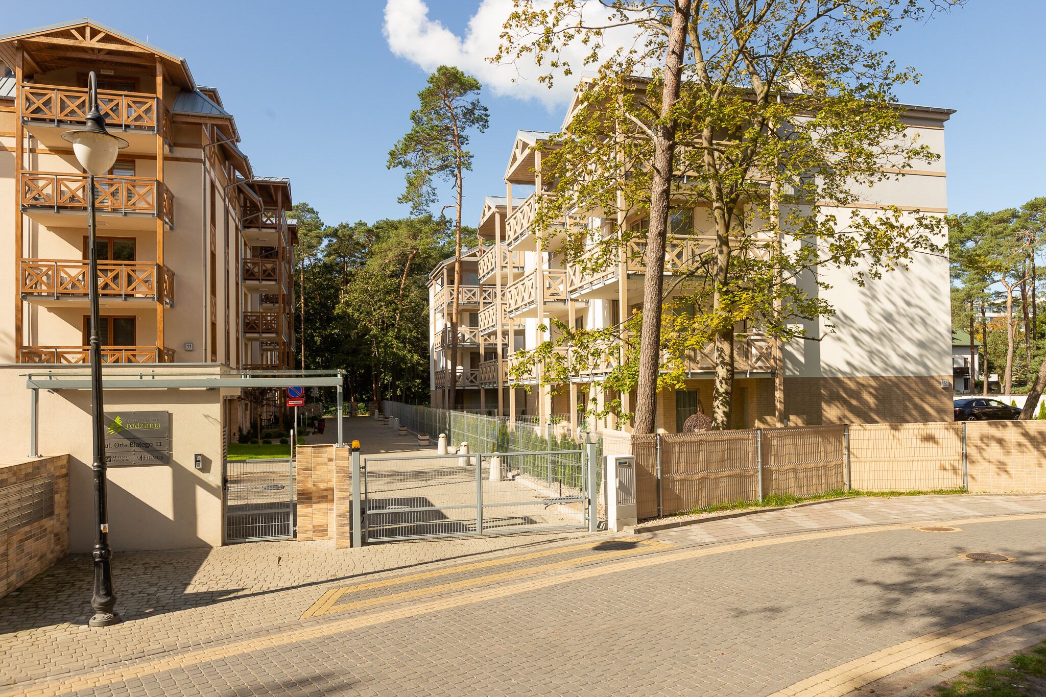 Un hotel de varios pisos con balcones, entrada vigilada y camino de acceso pavimentado.