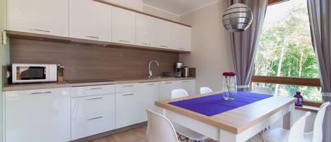 A modern kitchen with white cabinets, a microwave, and a dining area with a table and chairs.