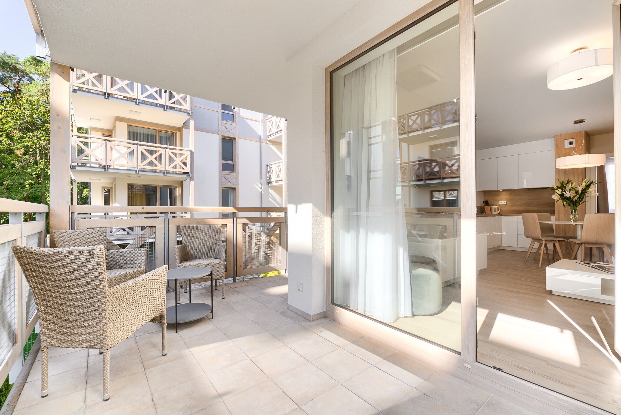 Un appartement moderne doté d’un balcon, aménagé avec des fauteuils et une table en osier.