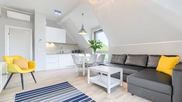 Ein modernes Wohnzimmer mit einer Couch, einem Couchtisch und einem Essbereich mit Stühlen.
