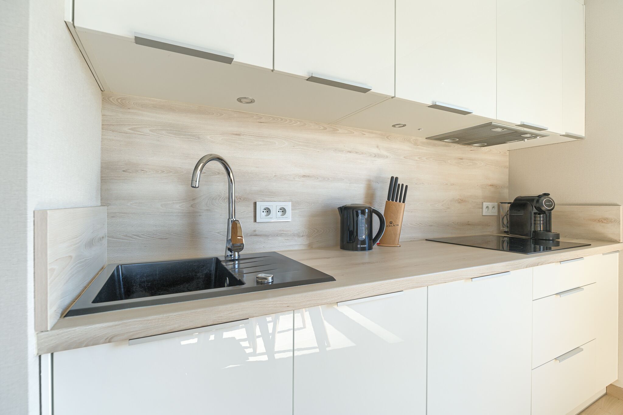 A modern kitchen with a wooden countertop, stainless steel sink, and a coffee maker.