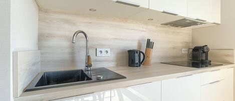 A modern kitchen with a wooden countertop, stainless steel sink, and a coffee maker.