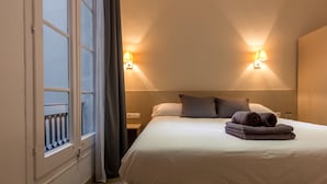 A hotel room with a bed, two bedside lamps, a window with curtains, and a nightstand. - Hostalin Barcelona Pg de Gràcia (Barcelona)