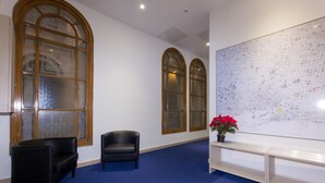A room with a large map on the wall, two arched windows, a blue carpet, and a bench. - Hostalin Barcelona Pg de Gràcia (Barcelona)