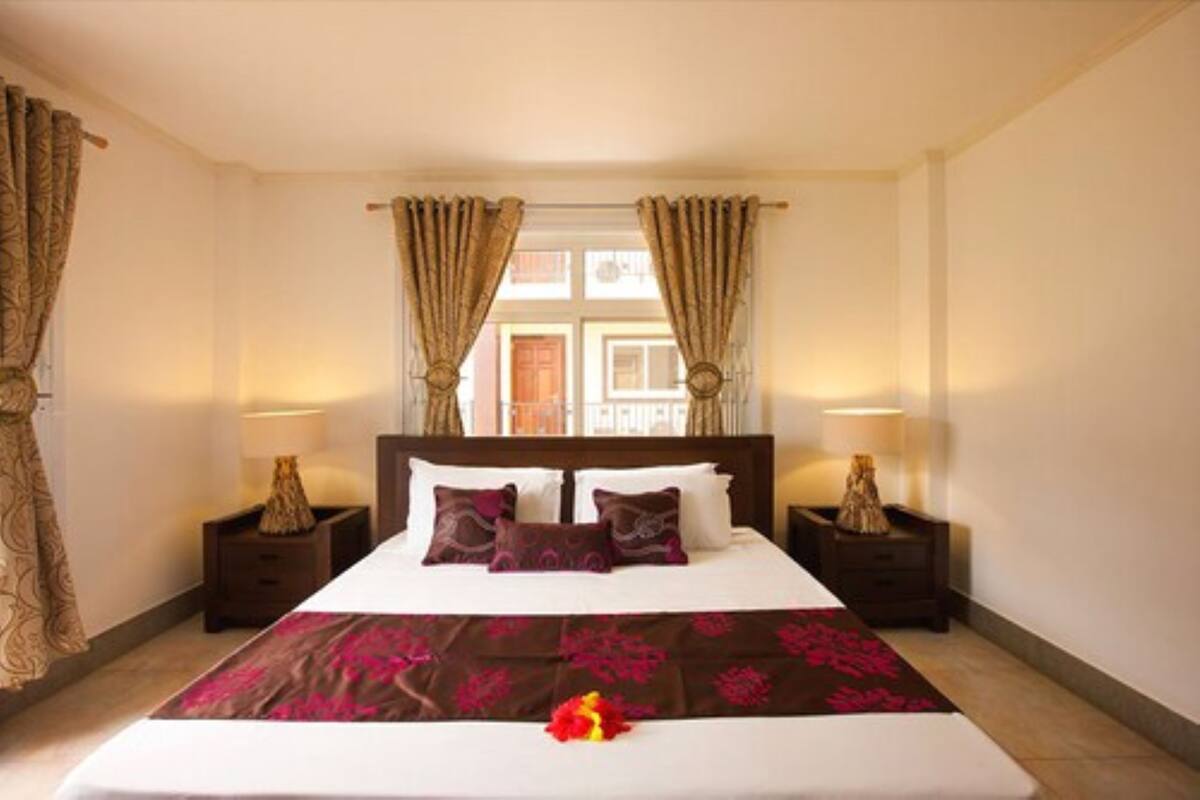 A hotel room with a large bed, two bedside tables with lamps, and curtains.