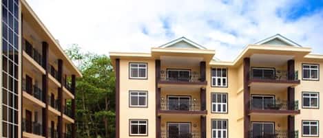 A multi-story residential building with balconies, large windows, and a flat roof.