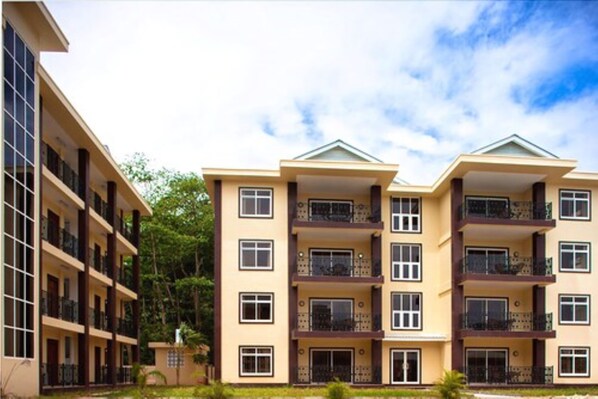 A multi-story residential building with balconies, large windows, and a flat roof.