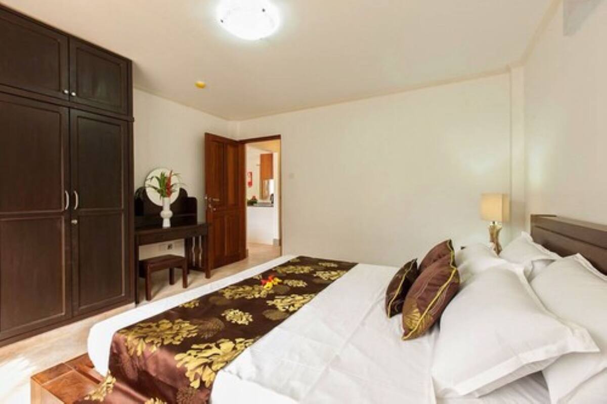 A hotel room with a large bed, a desk, and a wardrobe.