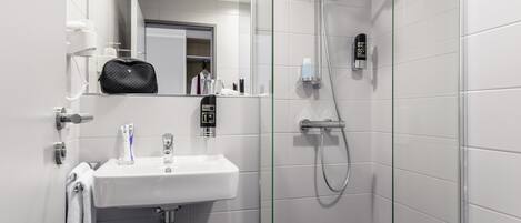 A modern bathroom with a glass shower enclosure, a white sink, and a mirror above it.
