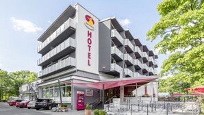 Un hotel moderno con un letrero llamativo, varios balcones y un área de restaurante.