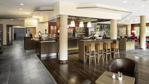 Un moderno vestíbulo de hotel con área de bar, asientos y una recepción.