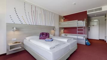 Ein Hotelzimmer mit zwei Betten, einem roten Teppich, einer Wand mit Punktmuster und einem Schlafkoje im Eck.