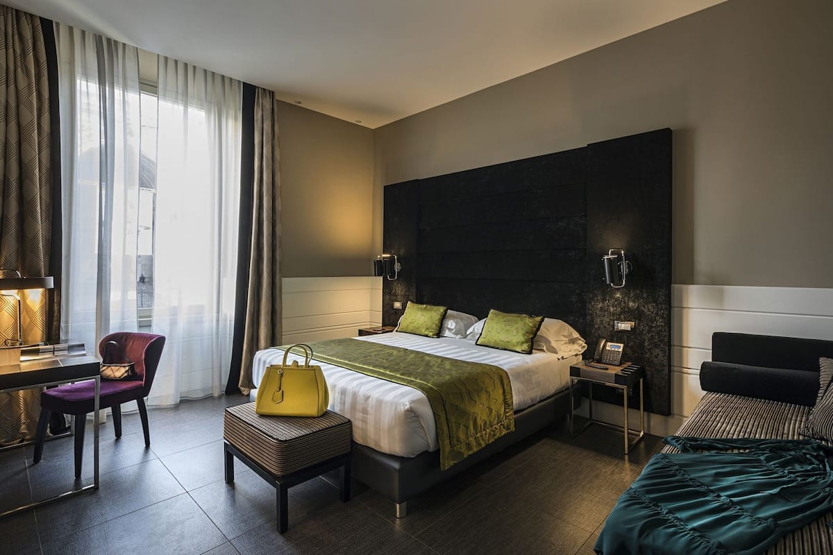 Une chambre d’hôtel comprenant un lit, un bureau, une chaise, une table de chevet et un canapé.