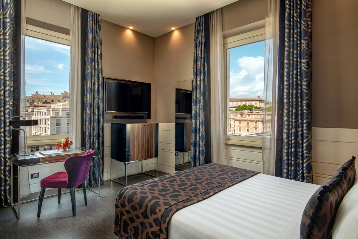 Une chambre d’hôtel équipée d’un lit, d’un bureau, d’une chaise et de deux téléviseurs.