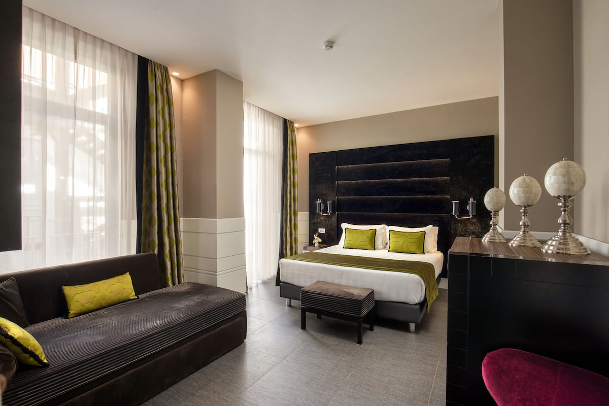 Une chambre d’hôtel moderne dotée d’un grand lit, d’un canapé, d’un bureau et offrant une vue sur la ville.