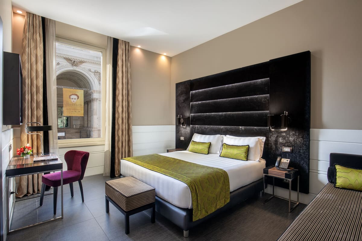 Une chambre d’hôtel moderne avec un grand lit, un bureau, une chaise et une petite table.
