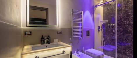 A modern bathroom with a large mirror, a sink, a bidet, and a glass-enclosed shower.
