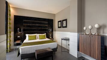 A modern hotel room with a large bed, bedside tables, a bench, a wardrobe, and a small side table.