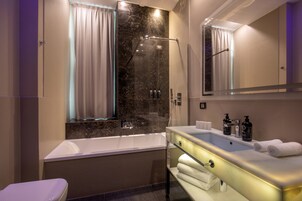 A modern bathroom with a glass-enclosed shower, a white bathtub, and a vanity with a mirror.