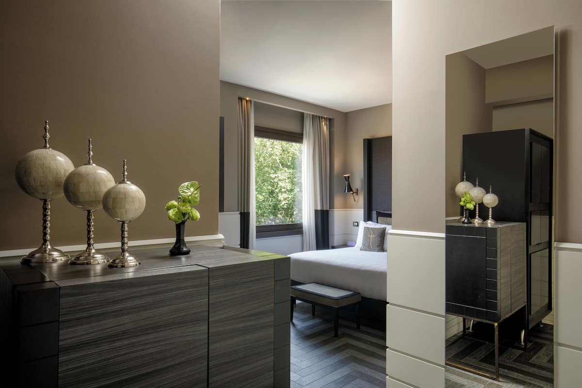 Une chambre d’hôtel moderne, équipée d’un lit, d’une table de chevet et d’une commode.