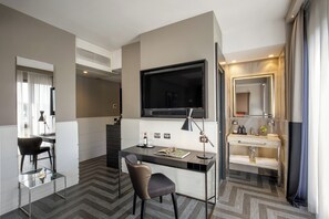 A modern hotel room with a desk, chair, TV, and bathroom.