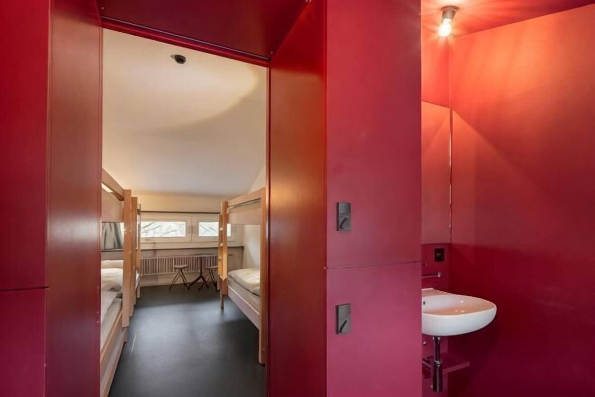 A corridor leading to a room with bunk beds, a sink, and a window.