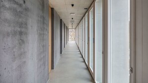 Un pasillo largo y estrecho con paredes de concreto y amplias ventanas a un lado.