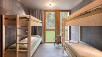 Habitación con literas, una mesita pequeña y una ventana.