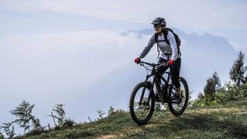 A mountain biker on a trail with a mountainous backdrop.