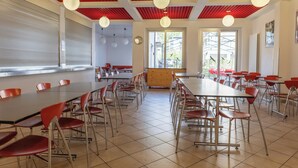 A spacious dining area with red chairs and tables, a red ceiling, and large windows allowing natural light. - Youth Hostel Locarno (Locarno)