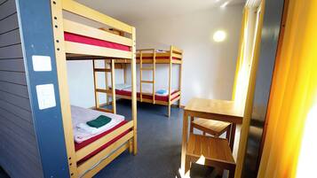 Un dormitorio con literas, un escritorio de madera y una silla.