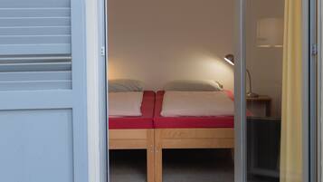 A bedroom with a bed, a nightstand, and a sliding glass door leading to a balcony.