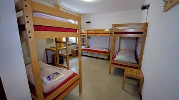 Una camera del dormitorio con letti a castello, un tavolino e un termosifone.