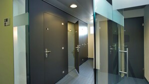 A modern hallway with dark-colored doors, a glass partition, and a tiled floor. - Youth Hostel Locarno (Locarno)