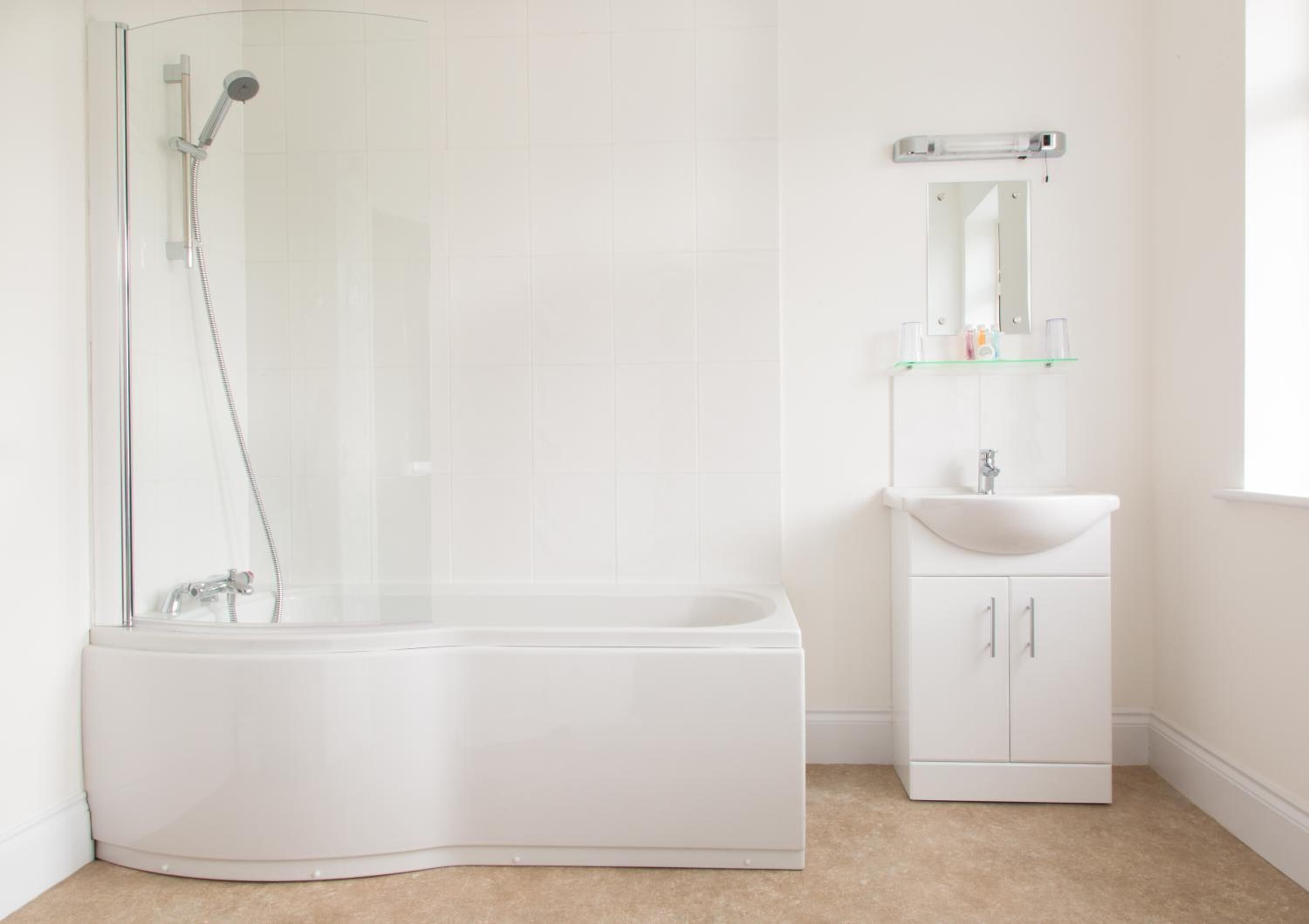 Une salle de bain moderne avec une douche à parois de verre, un lavabo blanc et un miroir au-dessus.
