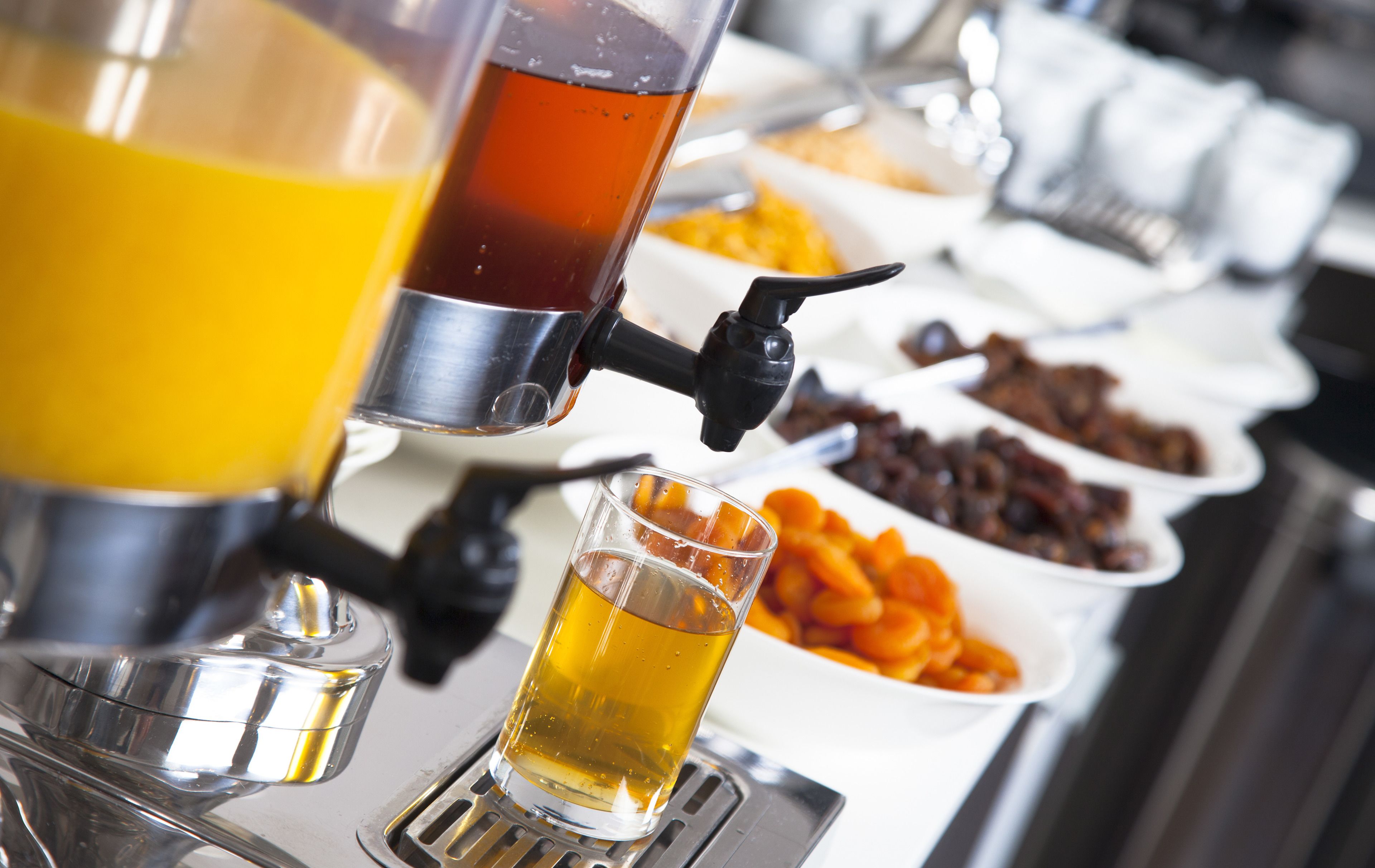 A beverage dispenser with a glass and a shot glass filled with a yellowish liquid.