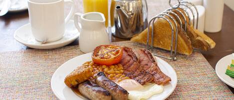 A breakfast plate with eggs, sausages, tomatoes, beans, and toast.