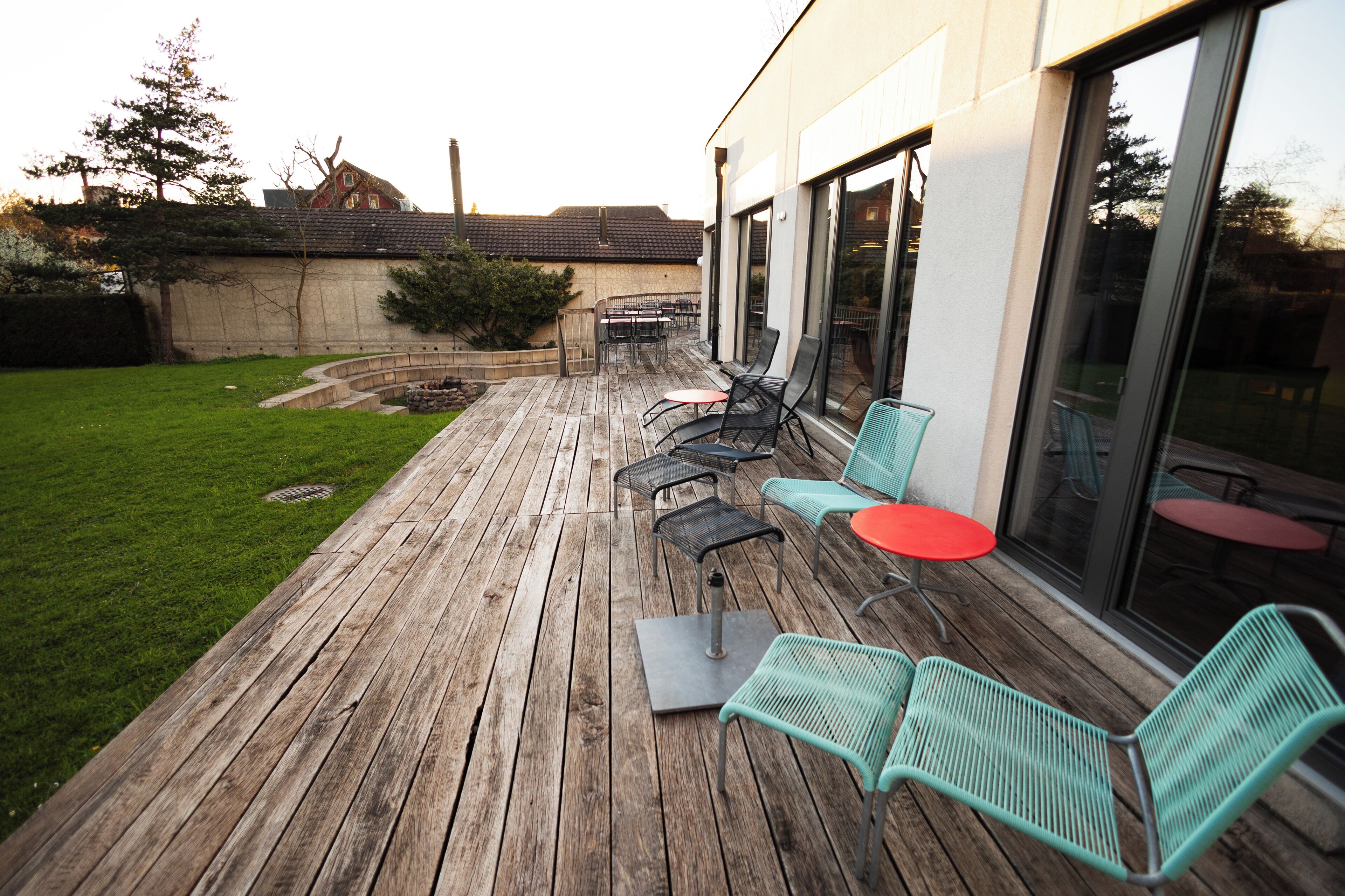 A wooden deck with outdoor seating, a small table, and a fire pit.