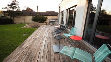 A wooden deck with outdoor seating, a small table, and a fire pit.