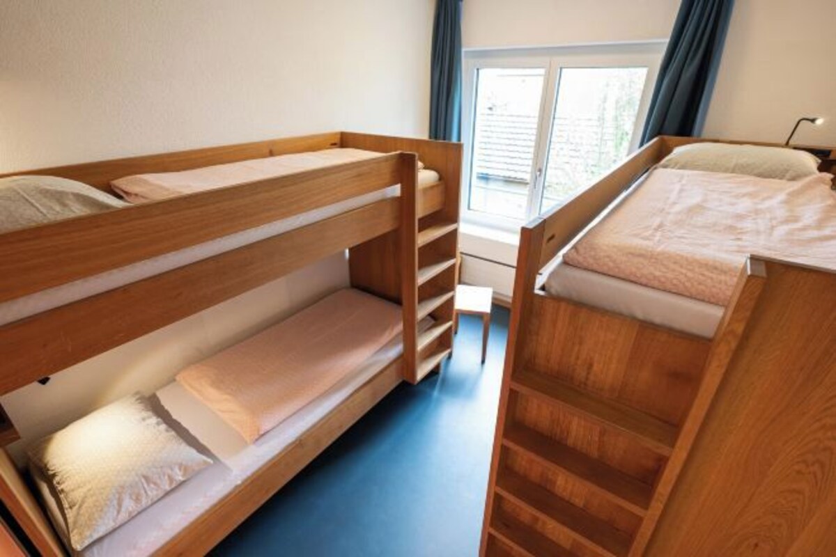 A bunk bed room with a window and a door.