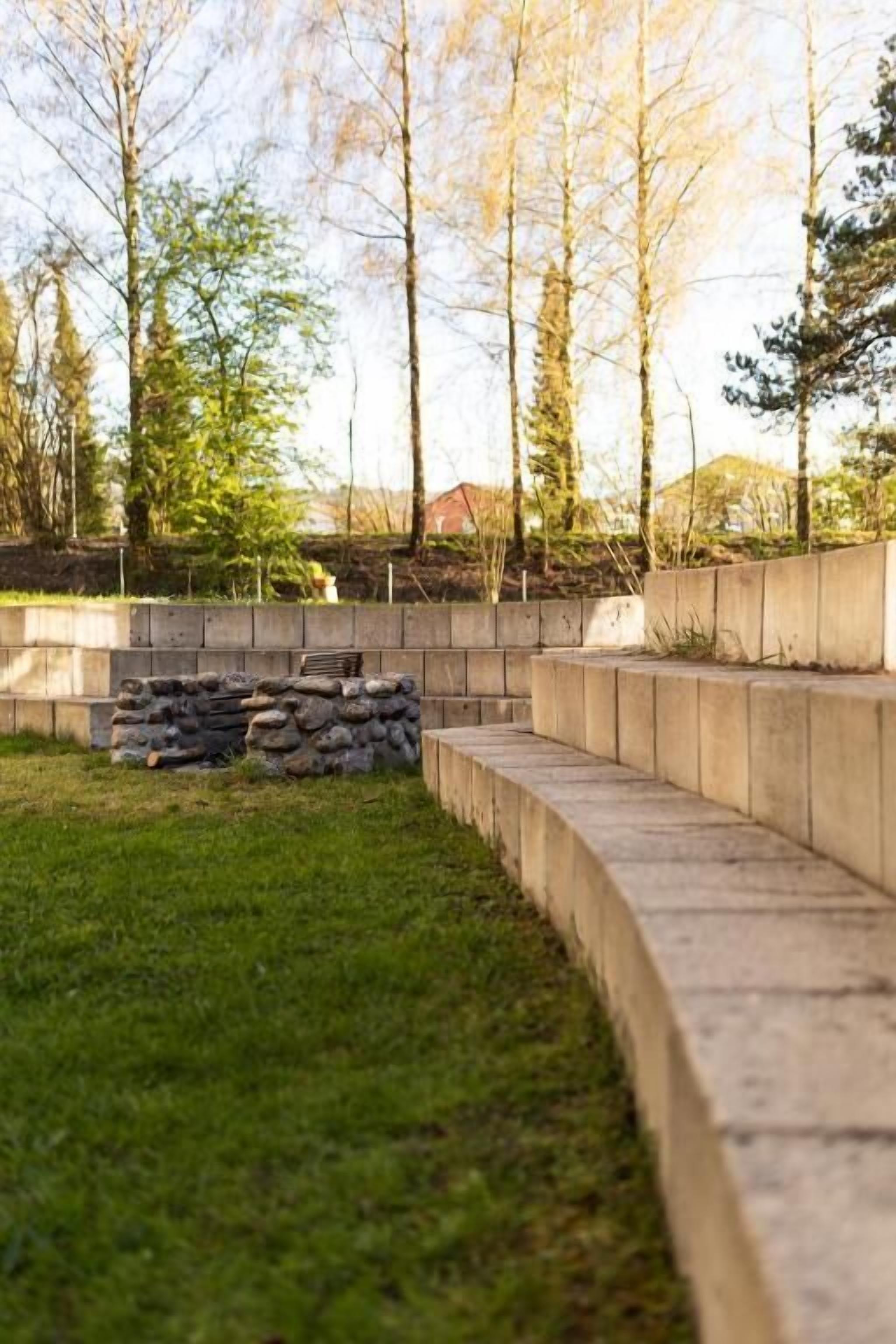 Un muro de piedra con escalones que bajan a una zona cubierta de césped.