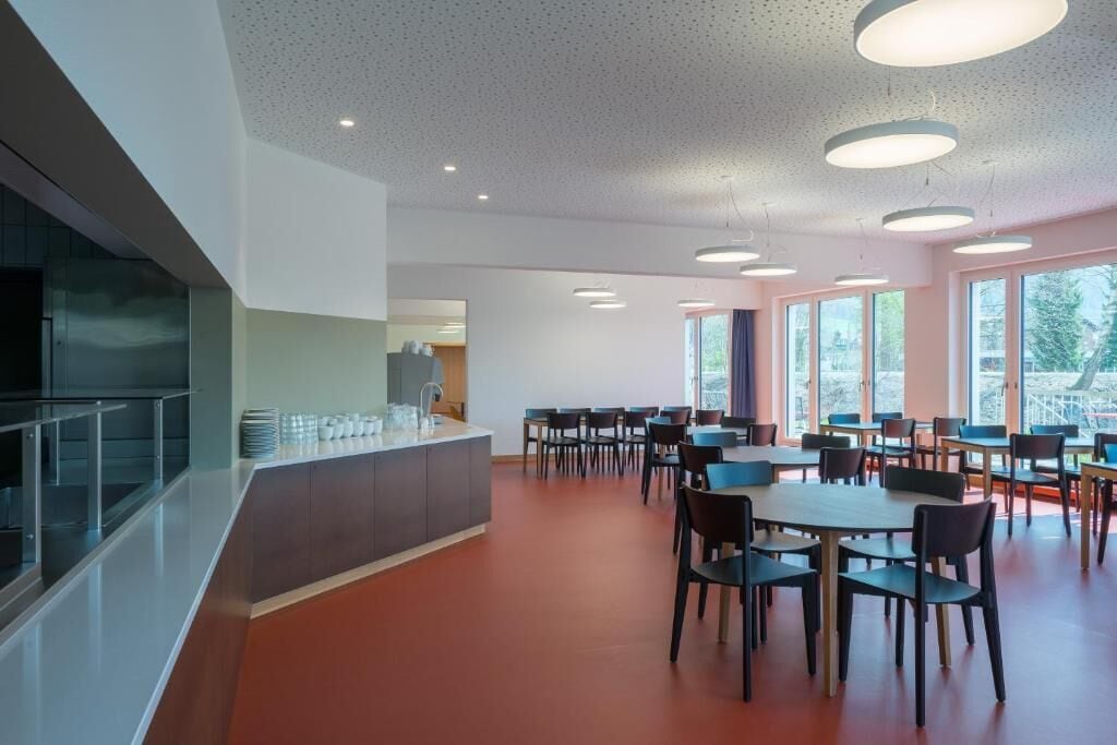 Ein moderner Essbereich mit einer zentralen Kochinsel, mehreren Tischen und Stühlen.