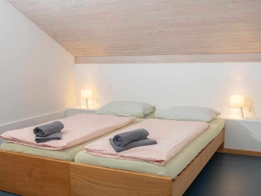 Ein Einzelbett mit zwei Kissen, einem hölzernen Kopfteil und zwei Nachttischlampen.